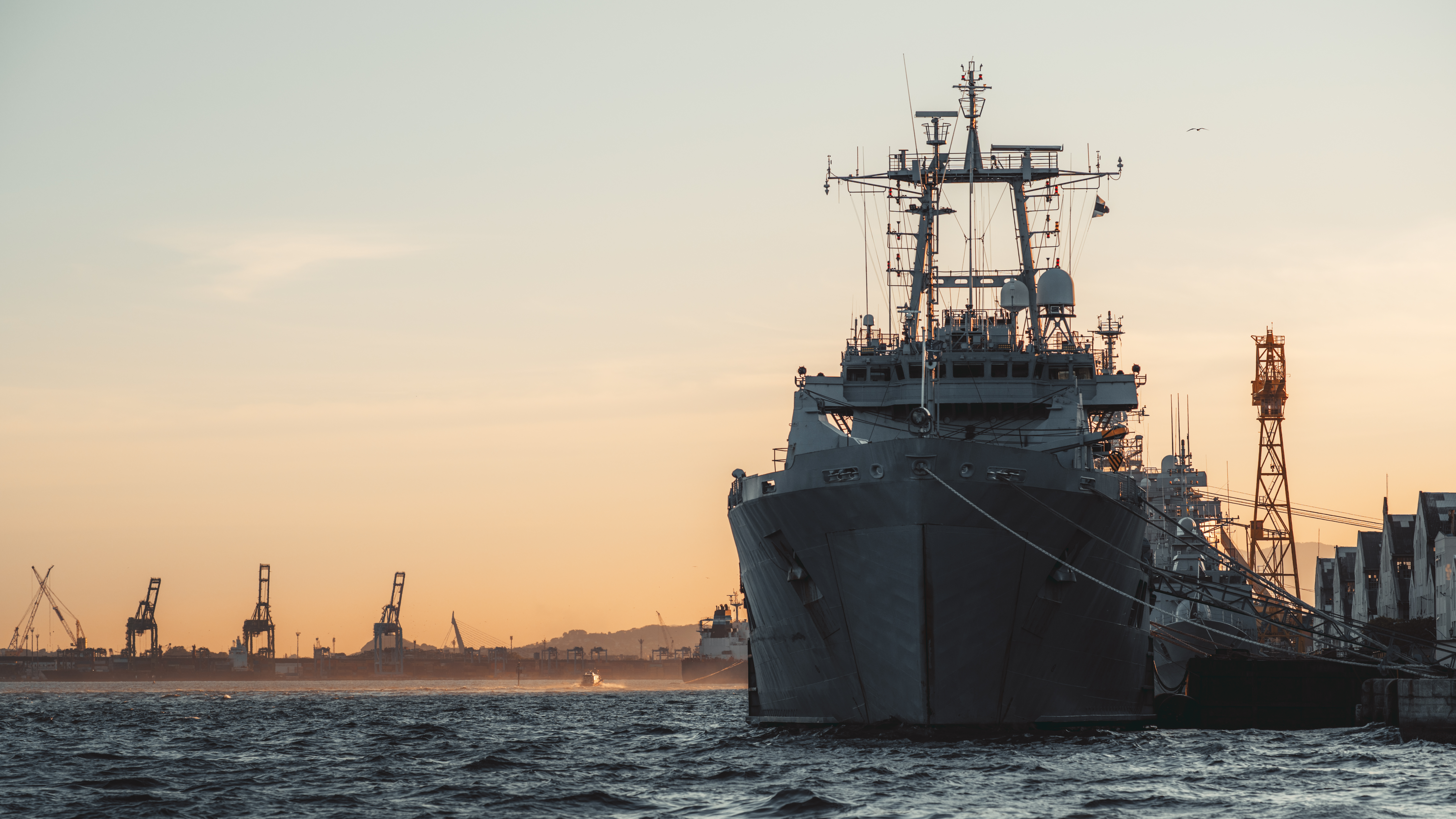 Warship docked at port at sunset